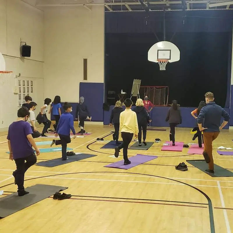 Students doing standing balance poses on mats in a school gym