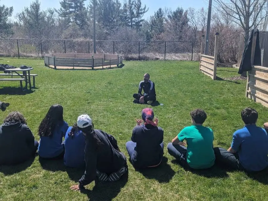 Soul Warrior Fitness session on the grass: the instructor sits facing a circle of students outdoors